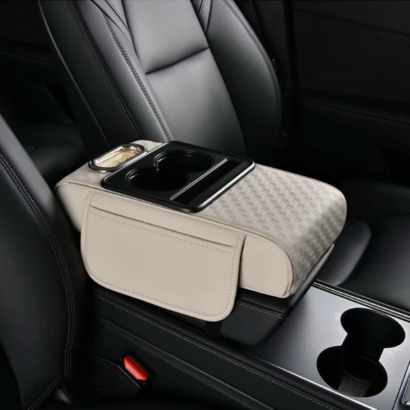 A beige car armrest cushion with integrated cupholders and storage is shown in a black car interior.