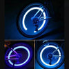 Close-up of motion-activated LED tire valve lights illuminating a bicycle wheel.