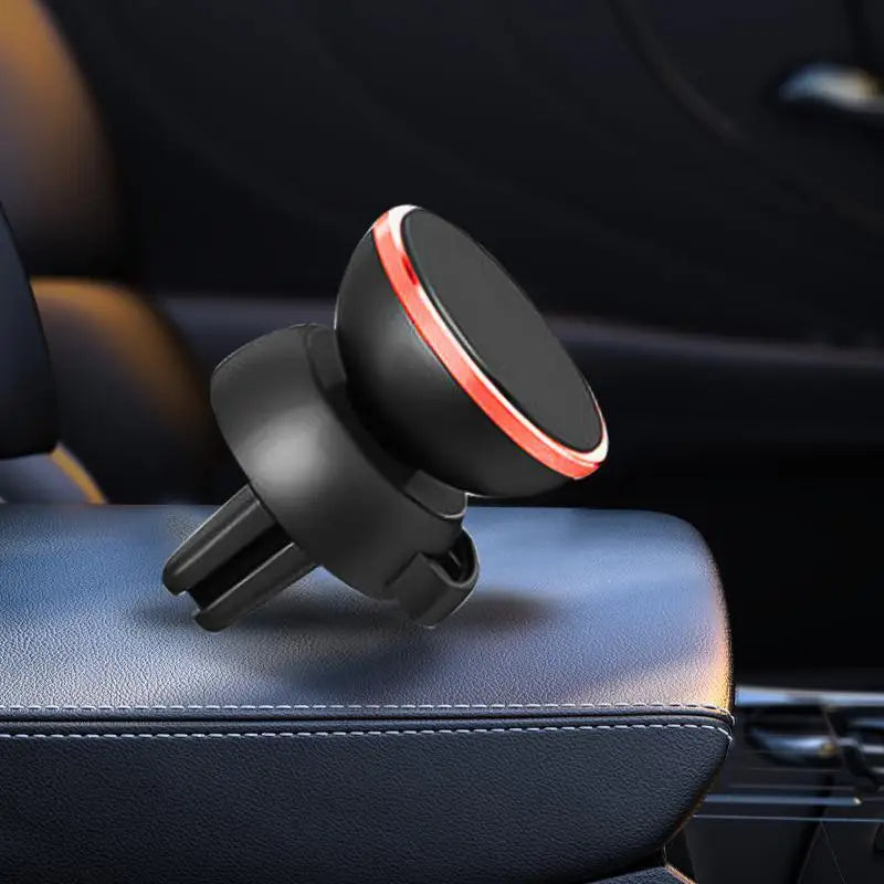 Support magnétique noir pour téléphone avec accent rouge sur un siège de voiture sombre.
