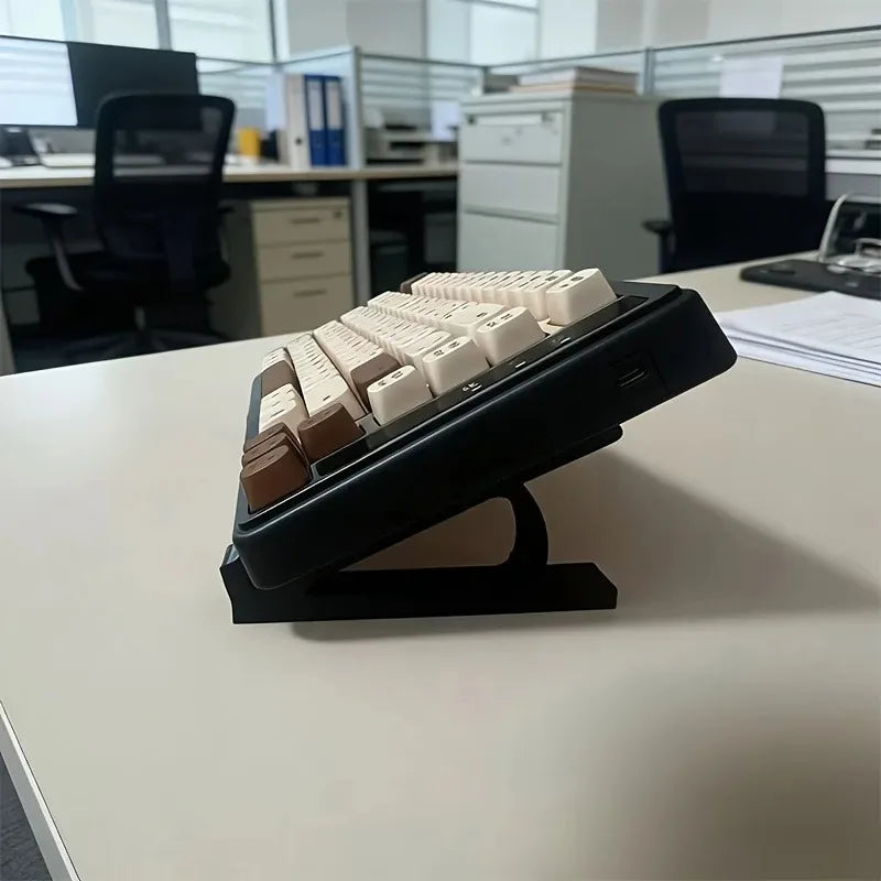 A black ergonomic keyboard riser with white keys is displayed on a white desk.