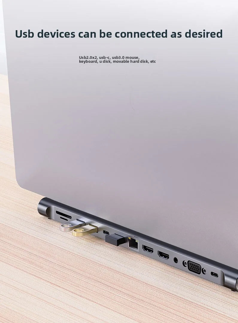 A silver USB-C docking station with multiple ports is shown lying on a wooden surface.