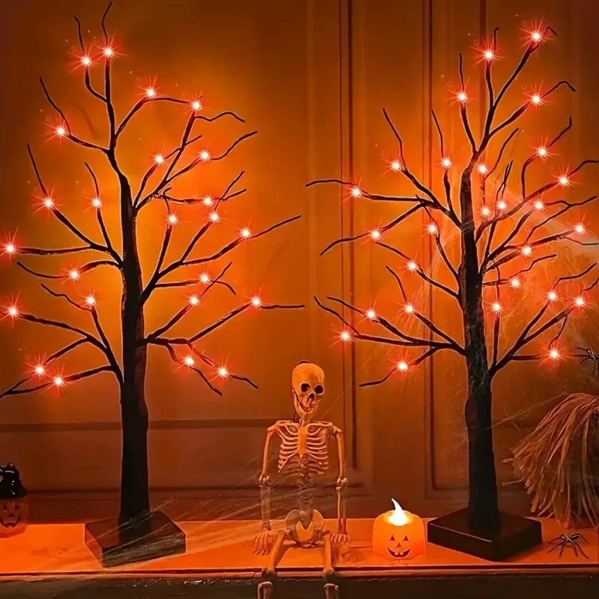 An LED Halloween birch tree with orange and purple lights stands next to a skeleton figure.