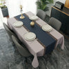A long dining table set with a gray tablecloth, white plates, and silverware in a modern interior.