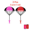Two colorful hand-thrown parachute toys, one pink and one red, shown with human figures for scale.