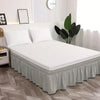 Un lit blanc avec une jupe élastique gris poussiéreux et décoration moderne.