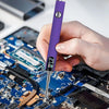 A hand holds a purple cordless USB-C soldering iron with a digital display tip over a blue circuit board.