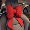 A red butterfly bow tie neck pillow with a textured cotton and linen cover is shown in a car interior.