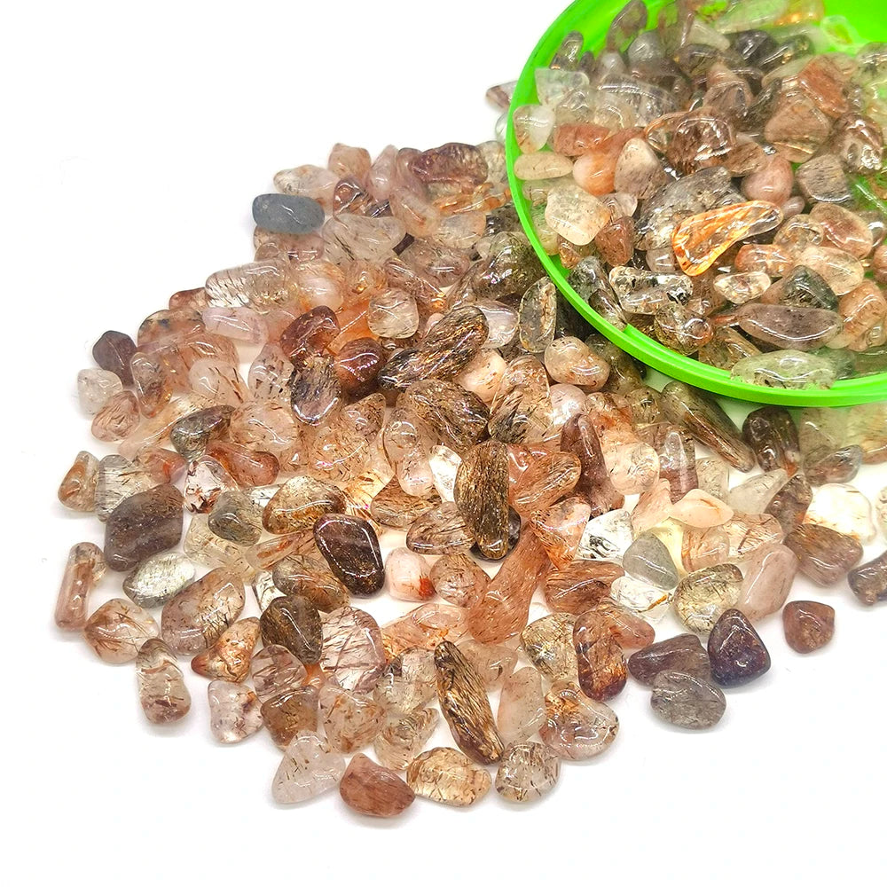 A pile of natural tumbled crystal stone chips in various shades of amber, brown, and clear quartz on a white background.
