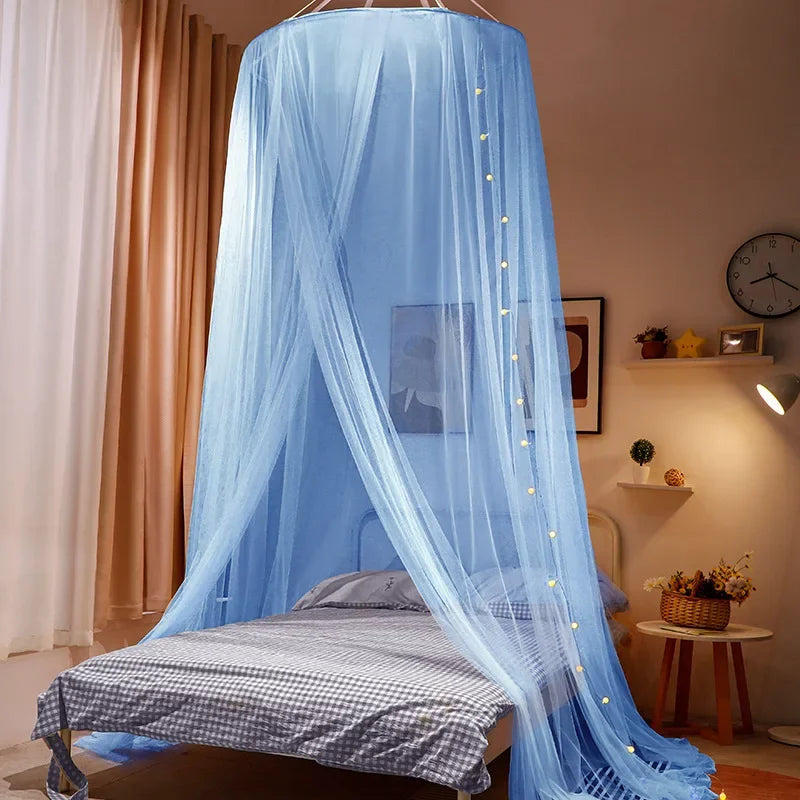 A light blue sheer canopy mosquito net draped over a double bed.