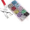 A plastic case containing various colored metal buttons and a pair of pliers for fastening projects