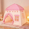 A pink flower playhouse tent for kids with scalloped trim and window details set up indoors.