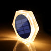 A hexagonal solar-powered LED step and path light with a blue solar panel illuminating the ground.