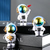 A white astronaut figurine with a clear helmet and red flag is displayed on stacked black books.