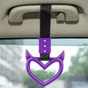 Purple heart-shaped ring drift handle with a black strap hanging from a car interior component.