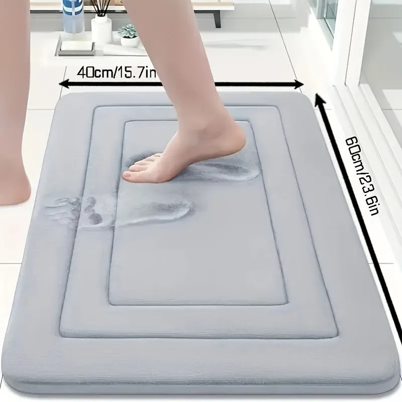 A gray absorbent soft non-slip bath mat is shown with a foot placed on it, demonstrating its size and texture.