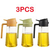 Three glass oil spray bottles in shades of yellow and green for cooking.
