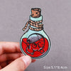 An embroidered patch depicting a skull with horns and a beard, tied with twine, on a light blue background.