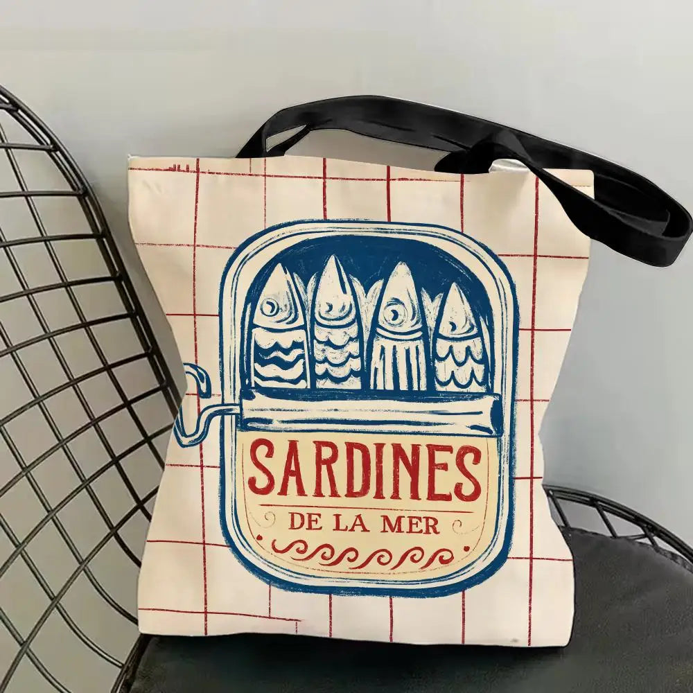 A canvas tote bag featuring a blue print of sardines on a red and white grid background.