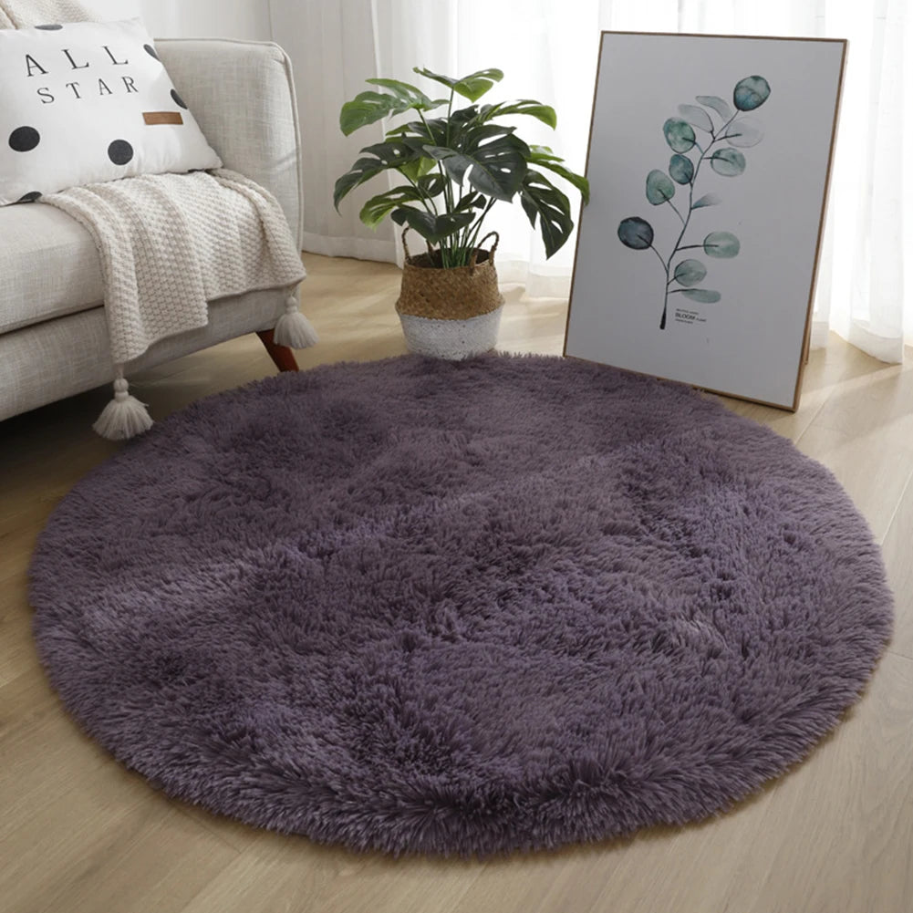 A round, dark purple shaggy rug placed on a light wooden floor next to a sofa and a potted plant.