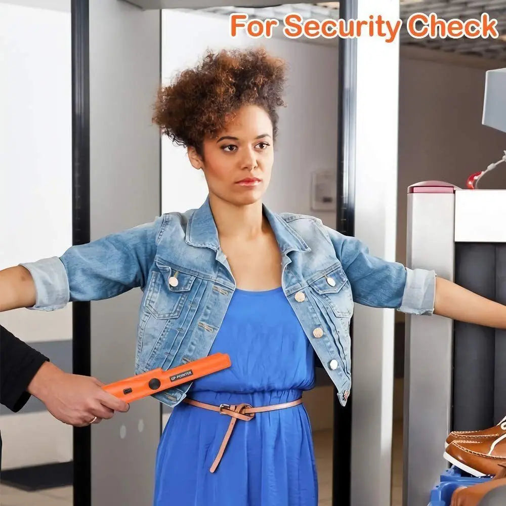 A woman wearing a blue dress and denim jacket is being scanned with a handheld metal detector for security check.
