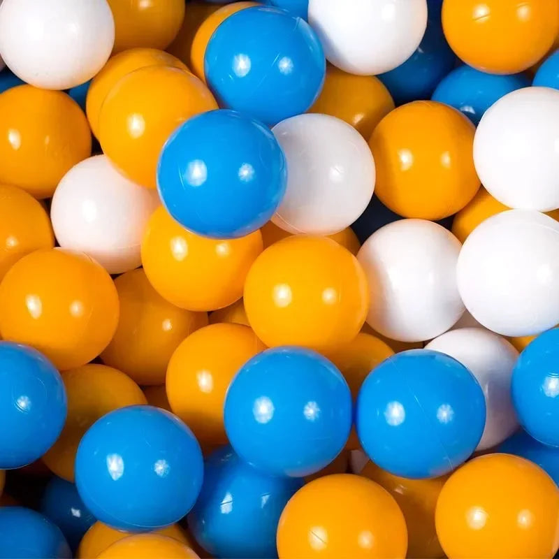 A close-up view of a large collection of colorful plastic ball pit balls in yellow, white, and blue.