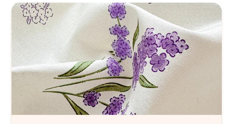 Nahaufnahme eines cremefarbenen Stoffes mit lila Lavendel-Blumendickunst und grünen Blättern