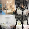 Floor-to-ceiling mosquito net with double opening draped over a bed.