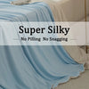 Light blue silky blanket draped over a bed, emphasizing no pilling or snagging.