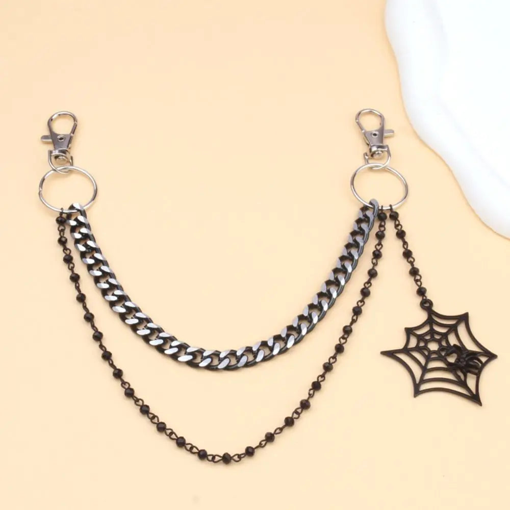 Silver metal chain strap with a black spider charm displayed on a beige background