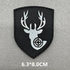 A black shield-shaped patch featuring a white deer antler silhouette with a crosshair target design.