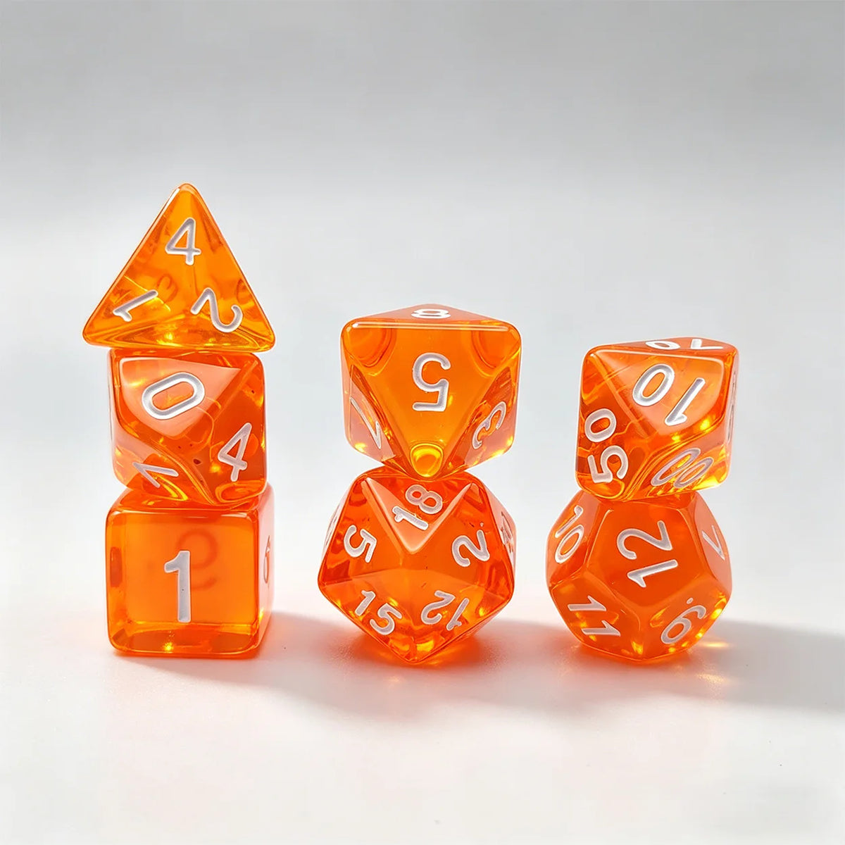 A set of seven translucent orange acrylic polyhedral dice, including a tetrahedron and several dodecahedral dice.