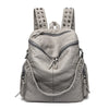 A light gray soft leather backpack featuring metal rivets and straps.