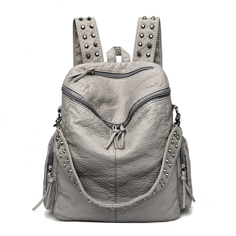 A light gray soft leather backpack featuring metal rivets and straps.