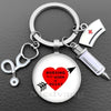 Silver necklace keychain featuring a heart design with the text Nursing is a work of heart and a medical syringe charm