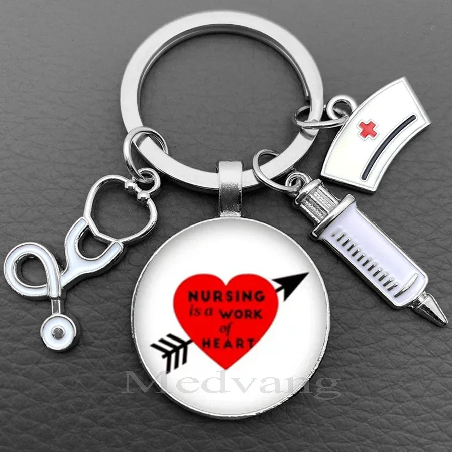 Silver necklace keychain featuring a heart design with the text Nursing is a work of heart and a medical syringe charm