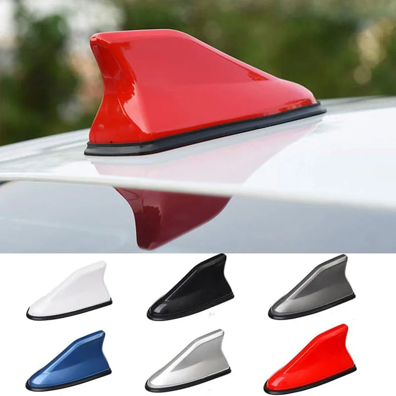A collection of aerodynamic shark fin car antennas in various colors including red, black, silver, and blue.