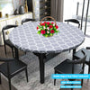 A round table set featuring a gray patterned elastic-edged vinyl tablecloth and black dining chairs.