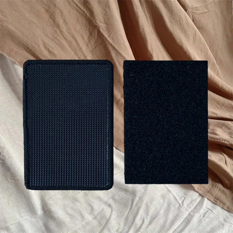 A pair of black tactical snake morale patches with hook-and-loop backing resting on a beige fabric.