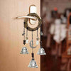 A decorative witch bells door hanger wind chime made of natural twine and glass hanging on a wooden door.
