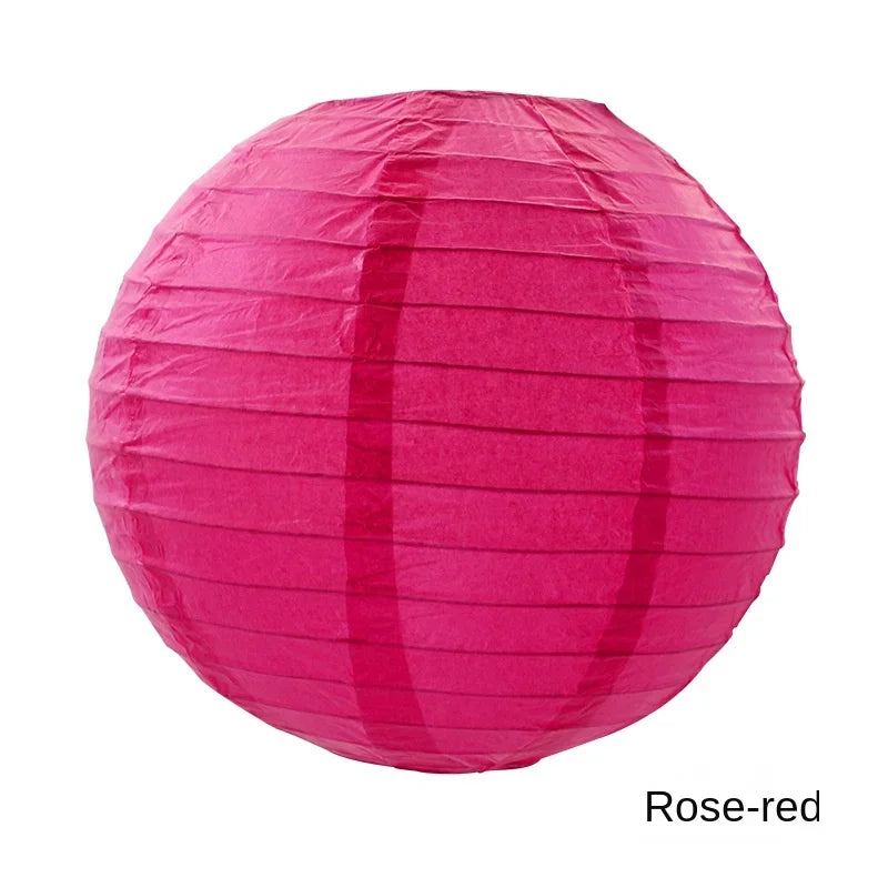 A round, pink paper lantern with vertical folds, colored rose-red.