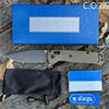 An ultralight EDC folding knife with a drop point blade, a blue box, and a black sheath are displayed on wood.