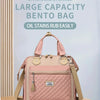 Rosa geteilte Bento-Tasche mit gesteppter Textur und braunen Trägern auf einer Holzoberfläche