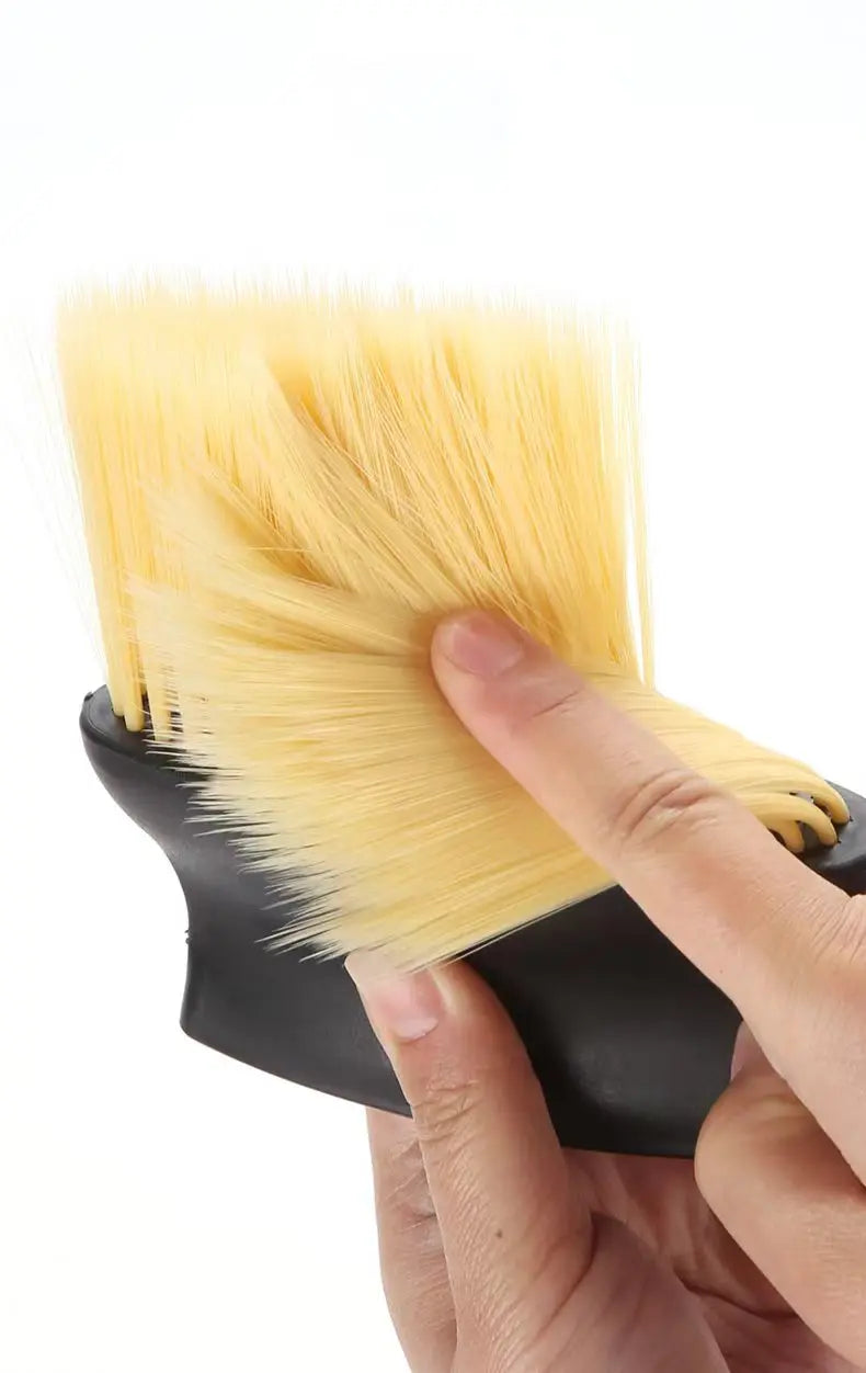 A hand holds a yellow car interior detailing brush set with soft bristles.