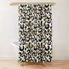 A leopard print shower curtain featuring black and gold spots hanging from a brass rod.