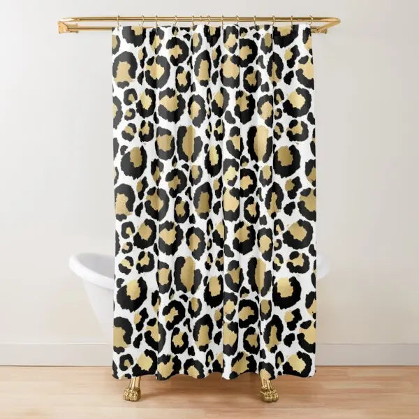 A leopard print shower curtain featuring black and gold spots hanging from a brass rod.