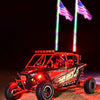 A red Can-Am Maverick X3 off-road vehicle with illuminated American flags mounted on the roof at night.