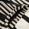 Close-up of a striped canvas tote bag showing the black and off-white pattern and stitching detail.