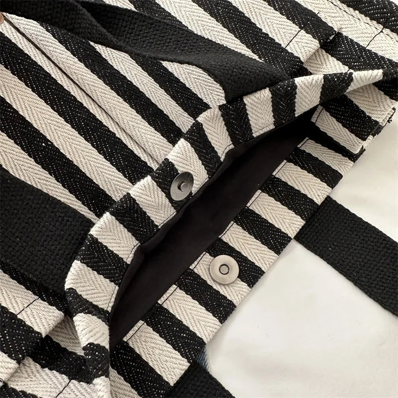 Close-up of a striped canvas tote bag showing the black and off-white pattern and stitching detail.