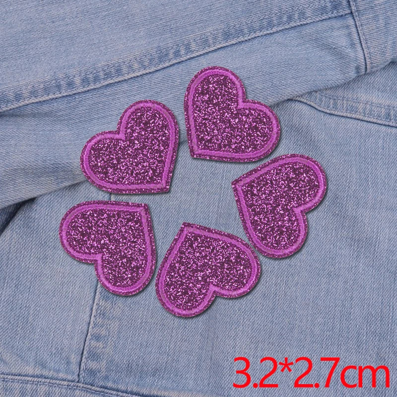 A set of five purple glitter heart iron-on embroidered patches on a denim fabric.