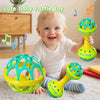 A smiling baby holding a yellow and green sensory rattle toy set with multiple spinning balls.